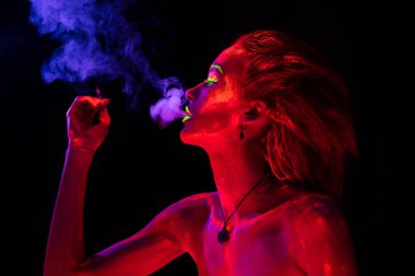 Vücudunda ultraviyole boya ile genç sigara seksi kız portresi. Siyah lamba ışığında parlayan bodyart güzel kadınla