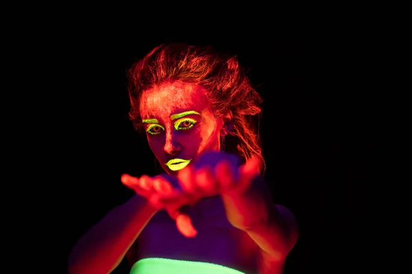 Una hermosa joven sexy con pintura ultravioleta en su cuerpo bailando en la oscuridad. Mujer bonita con el bodyart brillante en la luz de la lámpara negra — Foto de Stock