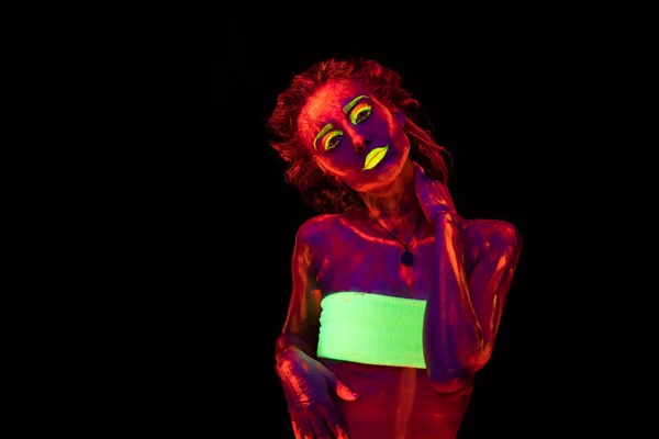 Egy szép fiatal szexi lány ultraibolya festék, a táncos a sötétben testén. Szép nő, a fekete lámpa fény izzó bodyart — Stock Fotó