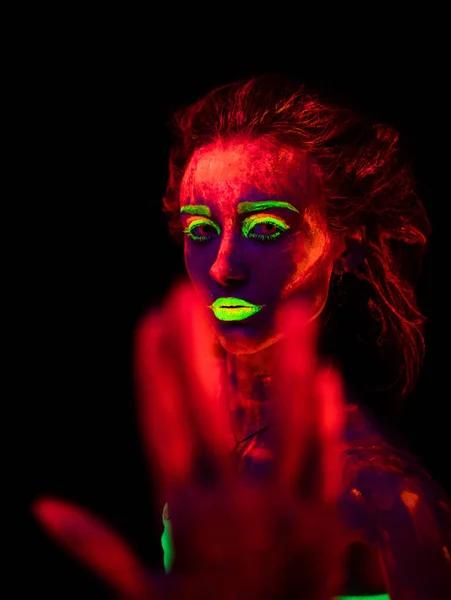 Красива молода сексуальна дівчина з ультрафіолетовою фарбою на її тілі танцює в темряві. Красива жінка з сяючим бодіарт в чорному ламповому світлі — стокове фото
