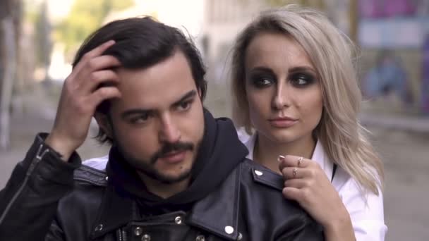 Young handsome biker guy in helmet and attractive blonde girl with smokey eyes are sitting on a bike in urban graffiti scene — Stock Video