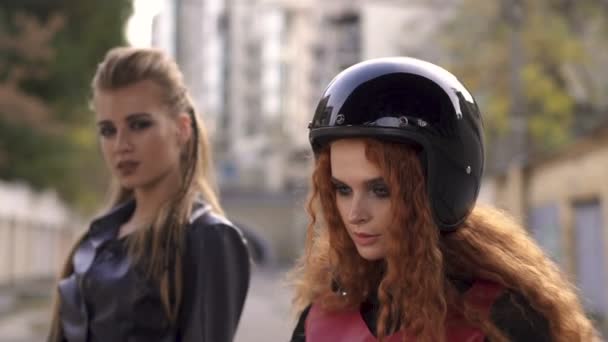 Duas meninas de couro de moda esquisita e motocicleta preta. Jovens mulheres punk sexy em cena de graffiti urbano — Vídeo de Stock