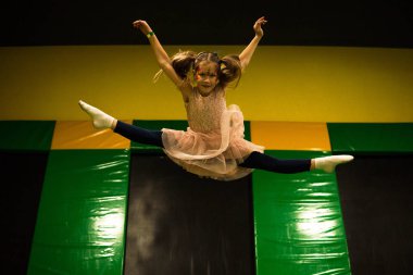 Bir trambolin üzerinde atlama ve sicim bölme yapma küçük kız çocukları için oyun odasında