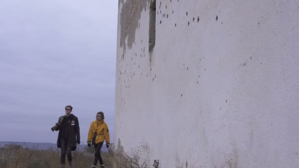 Couple of survivors with rifle and machete Near white bullet dotted wall in the misty and unkind urban ruines. Stalker in the post-apocalyptic world — Stock Video