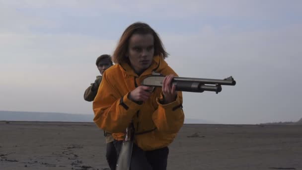 Man en meisje sluipt in bewolkt woestenij. Stalker - Survival concept. Echtpaar met vuurwapens wapens. Meisje met geweer en man met geweer. — Stockvideo