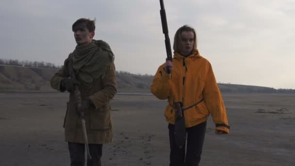 Man en meisje in bewolkt woestenij. Stalker - Survival concept. Echtpaar met vuurwapens wapens. Meisje met geweer en man met geweer. — Stockvideo