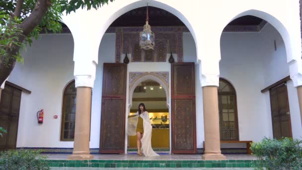 Beautiful Moroccan Girl Waving her white mantle in Picturesque Dar Si Said Riyad in Marrakech at sunset time — Stock Video