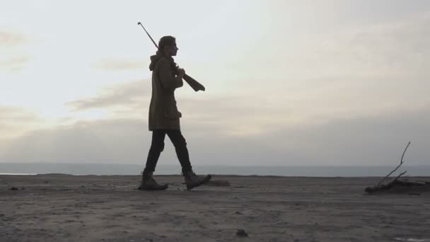 Giovane Stalker ragazzo con fucile e volto dipinto a piedi in terra desolata post apocatitica nuvoloso. Stalker - concetto di sopravvivenza — Video Stock