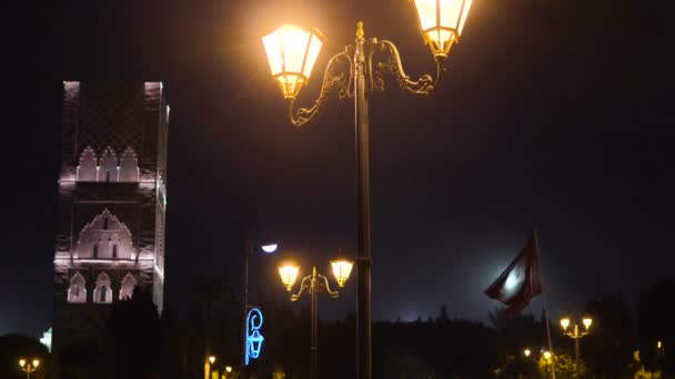 Éjszakai kilátás Hassan toronyról a négyzetből, amely lámpások és zászlók Rabatban, Marokkóban. Befejezetlen mecset minaret a király Hassan II mauzóleum. A legnagyobb afrikai civilizáció maradványa — Stock videók