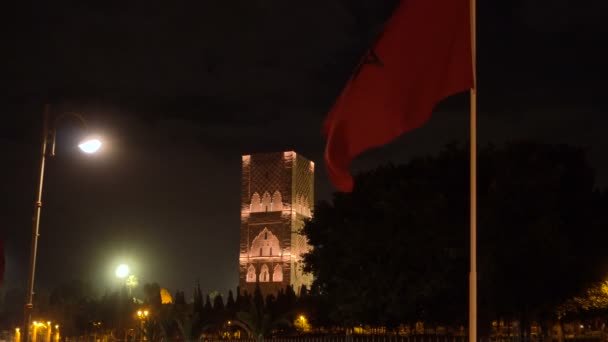 Νυχτερινή θέα στον πύργο Χασάν από την πλατεία με φανάρια και σημαίες στο Ραμπάτ του Μαρόκου. Ημιτελής Μιναρί τζαμί με θέα στο μαυσωλείο του βασιλιά Χασάν ΙΙ. Λείψανα μεγαλύτερου παλαιού πολιτισμού στην Αφρική — Αρχείο Βίντεο