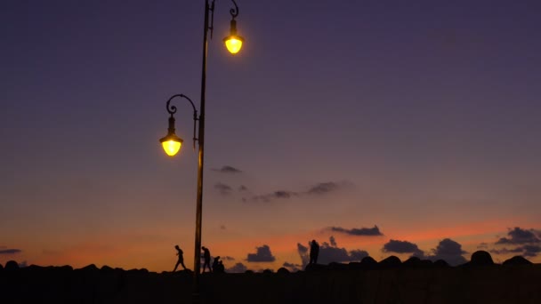 Silhuetas incríveis de pessoas passeando luz de fundo ao pôr do sol — Vídeo de Stock