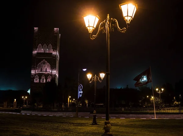 Widok nocny na wieży Hassana z placu z latarnie i flagi w Rabacie, Maroko. Niedokończony Meczet Minaret z widokiem na Mauzoleum króla Hassana II. Pozostałości największej starej cywilizacji w Afryce — Zdjęcie stockowe