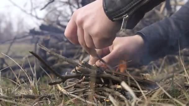 Handen van de mens het maken van een vreugdevuur op vroege voorjaar of herfst aard — Stockvideo