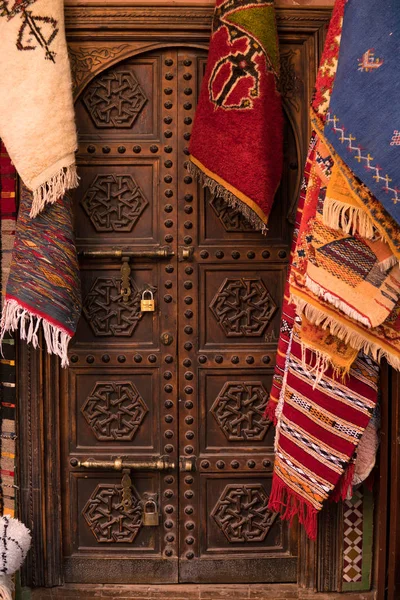 Porta histórica velha de madeira cercada com tapetes pendurados na rua de Marrakesh City, Marrocos — Fotografia de Stock