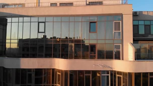 Fotografia aérea de arranha-céus de design moderno com janelas de vidro ao ar livre. Apartamento moderno edifício fachada de vidro refletindo outro arranha-céu de vidro no pôr do sol — Vídeo de Stock