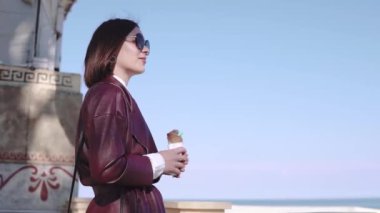 Sevimli şık esmer kız broadwalk tarafından yürüyüş ve güneşli bir günde dondurma yeme