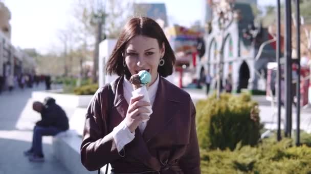 可爱的时尚黑发女孩走在宽阔的步行和吃冰淇淋在阳光明媚的日子 — 图库视频影像