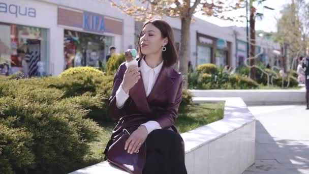 Чарівна стильна брюнетка дівчина гуляє на прогулянці і їсть морозиво в сонячний день — стокове відео