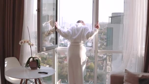 Attractive brunette woman in white bathrobe enjoying her new apartments for vacation on 21th floor — Stock Video