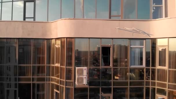 Légi felvétel a Hi-tech felhőkarcoló üveg mirrow ablakok szabadban. Táncoló nő fürdőköpenyben ablakban modern lakás épület üveg homlokzata tükrözi másik felhőkarcoló naplementekor — Stock videók