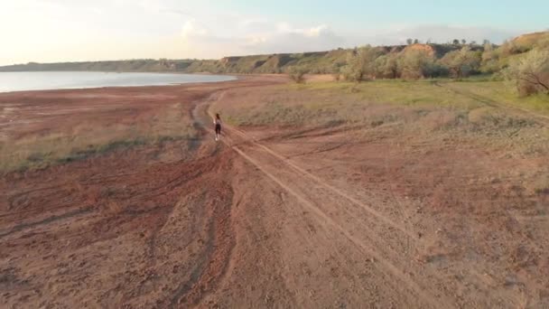 Aerial Shot av unga sportig kvinna som kör utomhus nära sjön eller Liman under vacker soluppgång eller solnedgång — Stockvideo