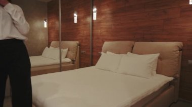 Kiralık dairelerde büyük aynaları olan rahat yatak odasının tadını çıkaran bir kadın. Kötü bir şeyin üstüne atlamak.