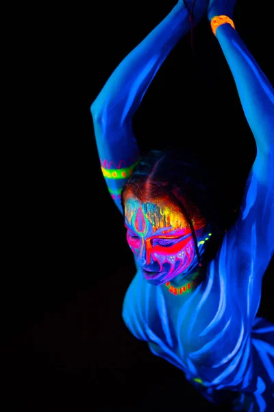 Portrait of Young naked bodyarted woman in in hitting action. blue glowing ultraviolet paint with big machete knife. Agressive avatar warrior woman amazon with pigtails hairstyle — Stock Photo, Image