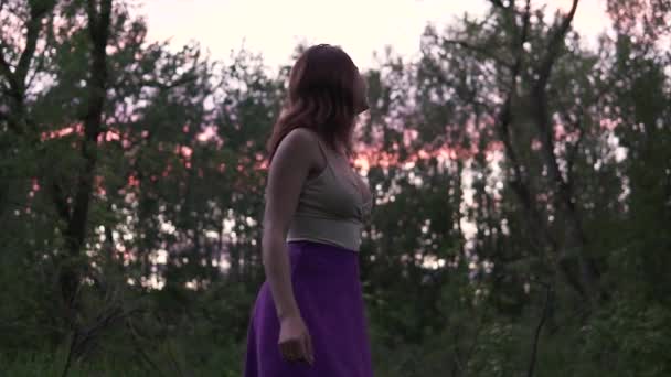 Joven hermosa mujer feliz con el pecho grande dando vueltas descalzo en el bosque en una falda púrpura en el crepúsculo — Vídeos de Stock