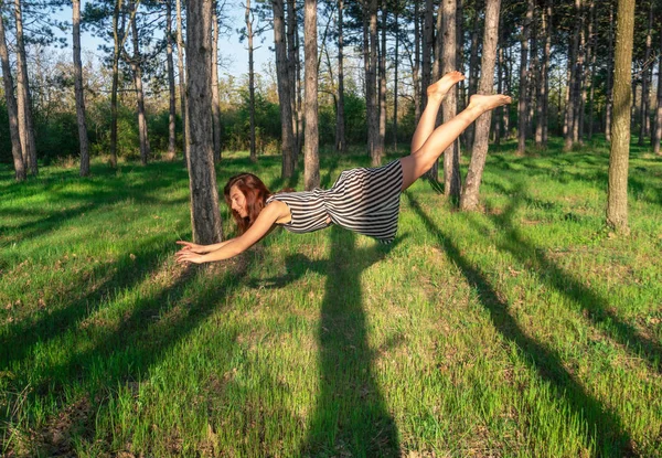 Jovem cabeça vermelha mulher levitando na floresta de pinheiros — Fotografia de Stock