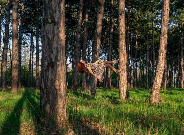 Jovem cabeça vermelha mulher levitando na floresta de pinheiros — Fotografia de Stock