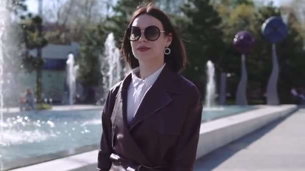 Lyxig vacker kvinna i Bourgogne jacka klänning promenad nära fontänen — Stockvideo