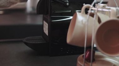 Kadın elleri kahve espresso makinesinden çıkan taze kahve yiyişiyor. Seramik kahve fincanında espresso yapma.