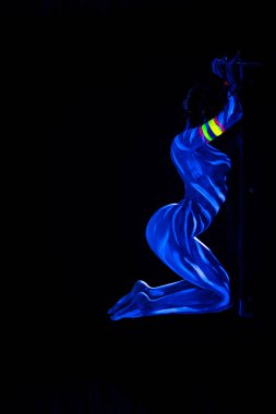 Mavi parlayan ultraviyole boya hareket ve alay genç çıplak bodyarted kadın. Seksi çıplak kız dans