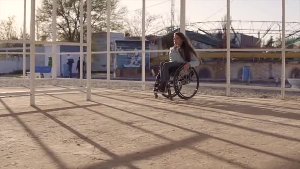 Jeune femme handicapée en fauteuil roulant se reposant sur la plage dans la région pour les personnes handicapées au soir automne ou printemps — Video