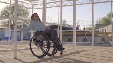Akşam sonbahar veya ilkbahar aylarında engelliler için bölgede sahilde dinlenen tekerlekli sandalyeli genç engelli kadın