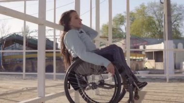 Akşam sonbahar veya ilkbahar aylarında engelliler için bölgede sahilde dinlenen tekerlekli sandalyeli genç engelli kadın