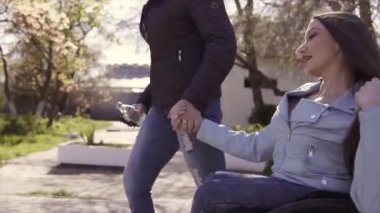 Aile eğlencesi. Tekerlekli sandalyedeki genç engelli kadın, annesi yle birlikte deniz kenarında yürürken, konuşup eğleniyor