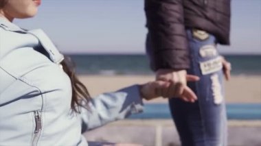 Aile eğlencesi. Tekerlekli sandalyedeki genç engelli kadın, annesi yle birlikte deniz kenarında yürürken, konuşup eğleniyor