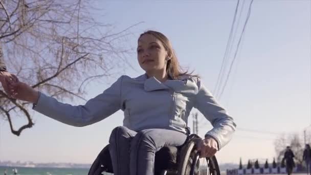 Familie vrije tijd. Jonge gehandicapte vrouw in rolstoel met haar moeder wandelen in de buurt van de zee, spreken en plezier hebben — Stockvideo