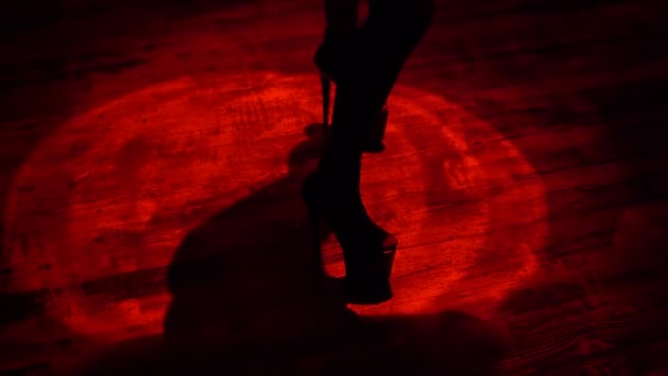 Sexy femmes jambes en talons hauts dansant en faisceau de lumière rouge à l'intérieur de strip-tease bar night club 