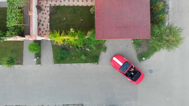 Ein erfolgreiches Paar im roten Cabrio-Sportwagen parkt in der Nähe des elitären Dorfhauses und kommt nach Hause. Luftaufnahme. — Stockvideo