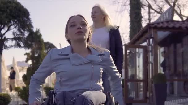 Familie vrije tijd. Jonge gehandicapte vrouw in rolstoel met haar moeder wandelen in de buurt van de zee, spreken en plezier hebben — Stockvideo