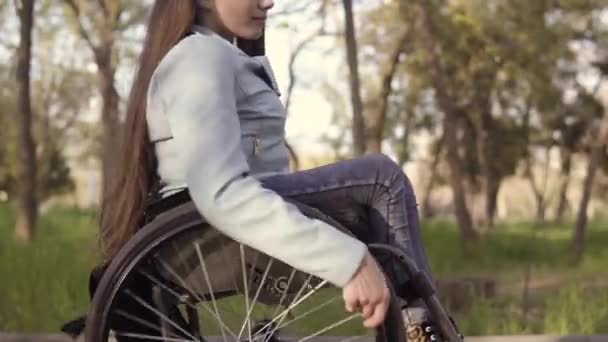 Giovane bella donna disabile in sedia a rotelle a piedi nel parco di sera — Video Stock