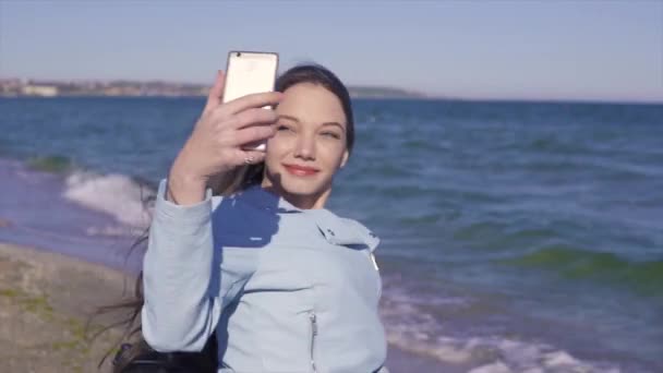 Młoda kobieta niepełnosprawna na wózku zabawy na piaszczystej plaży w pobliżu morza. Fotografowanie z telefonem i robienie selfie — Wideo stockowe