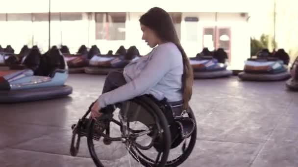 Junge behinderte Frau tanzt im Rollstuhl auf der Attraktionsfläche der Elektroautos — Stockvideo