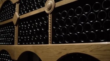 Mahzende yatan şarap şişeleri. Taş mahzende ahşap raflar saklanan kırmızı şarap cam şişeler. Şaraphanede iç yeraltı şarap mahzeni