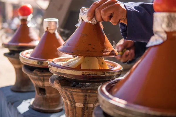 Morroco sokakta şehir meydanında bir açık barbekü buhar buharı geleneksel Tajine pişirme adam bir el