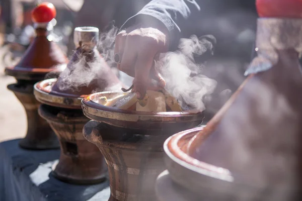 Eine Hand des Mannes kocht traditionelle Tajine in Dampf auf einem Grill im Freien am Stadtplatz auf der Straße in Marokko — Stockfoto