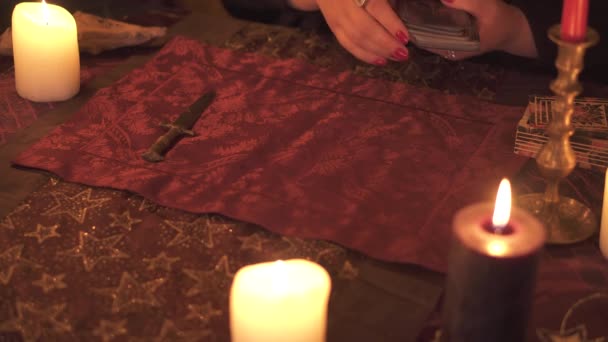Mulher caixa da sorte no quarto escuro com muitas velas adivinha em um baralho de tarô usando layout de cartão — Vídeo de Stock