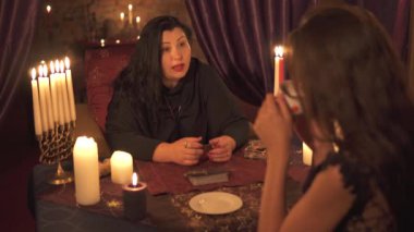 Mumlar çok karanlık odada Falcı kadın tarot kart destesi ile müşteriye geleceğin bir açıklama verir